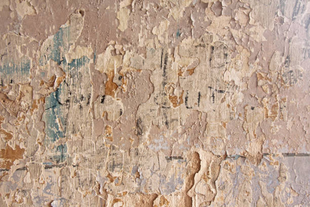 istock Old flaky white paint peeling off a grungy cracked wall. Cracks, scrapes, peeling old paint and plaster on background of old cement wall. An old cement stone wall as vintage cracked. Brick wall. 955998710