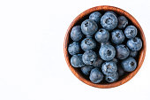 Fresh blueberries in wooden bowl on white background