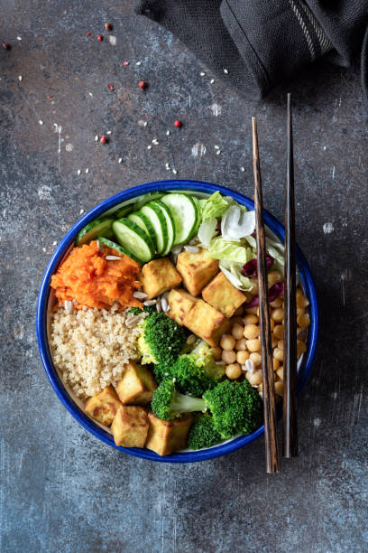 キヌア、豆腐、ブロッコリー、ひよこ豆と野菜のサラダ。鉢の石仏 - rainbow peppercorns ストックフォトと画像