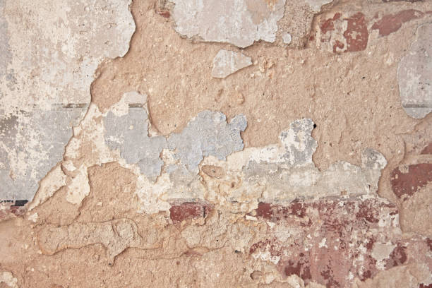 istock Old flaky white paint peeling off a grungy cracked wall. Cracks, scrapes, peeling old paint and plaster on background of old cement wall. An old cement stone wall as vintage cracked. Brick wall. 955999480