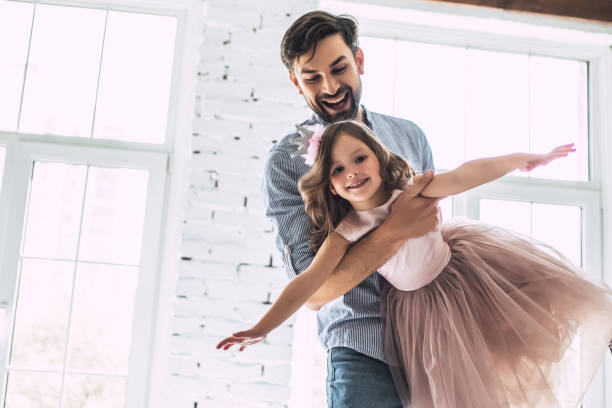 Dad with daughter at home I love you, dad! Handsome young man is dancing at home with his little cute girl. Happy Father's Day! dancing dad stock pictures, royalty-free photos & images