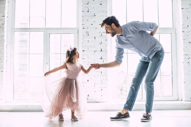 I love you, dad! Handsome young man is dancing at home with his little cute girl. Happy Father's Day!