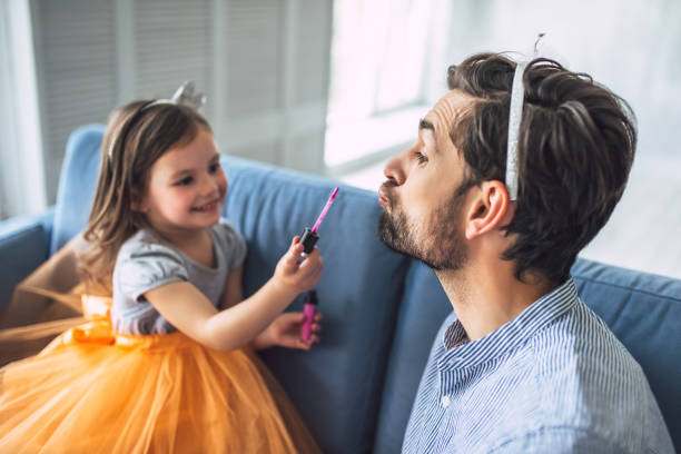 Dad with daughter at home I love you, dad! Handsome young man at home with his little cute girl. Daughter is doing makeup for her daddy. Happy Father's Day! happy fathers day funny stock pictures, royalty-free photos & images