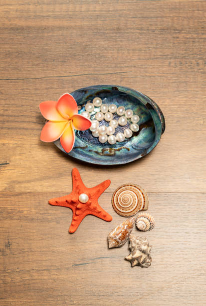 木製のテーブルにプルメリアの花とオレンジのヒトデとパール ホワイト - pearl shell starfish beach ストックフォトと画像