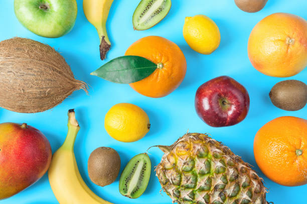 istock Pattern from Different Tropical and Seasonal Summer Fruits. Pineapple Mango Coconut Citrus Oranges Lemons Apples Kiwi Bananas Scattered on Light Blue Background.Healthy Lifestyle Vitamins. Flat Lay 956004982