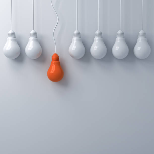 istock Think different concept , One hanging orange light bulb standing out from the dim unlit white light bulbs on white wall background , leadership and individuality creative idea concepts . 3D rendering 956014698