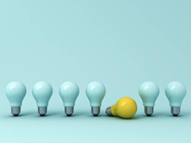 istock Think different concept , One yellow idea bulb lying down with the standing unlit light bulbs on blue pastel background with shadows , leadership and individuality creative concepts . 3D rendering 956014868