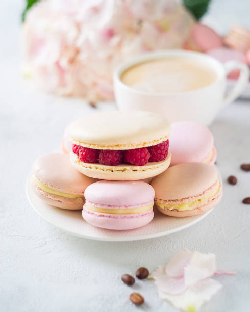 istock Macaroons and cup of coffee with flowers over white texture 956016932
