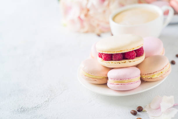 istock Macaroons and cup of coffee with flowers over white texture 956016948