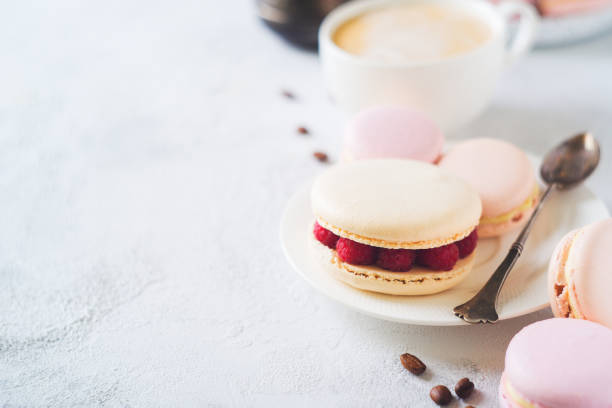 istock Macaroons and cup of coffee with flowers over white texture 956016992