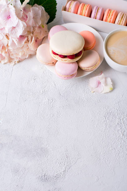 istock Macaroons and cup of coffee with flowers over white texture 956017004
