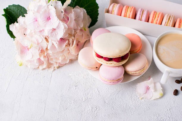 istock Macaroons and cup of coffee with flowers over white texture 956017072