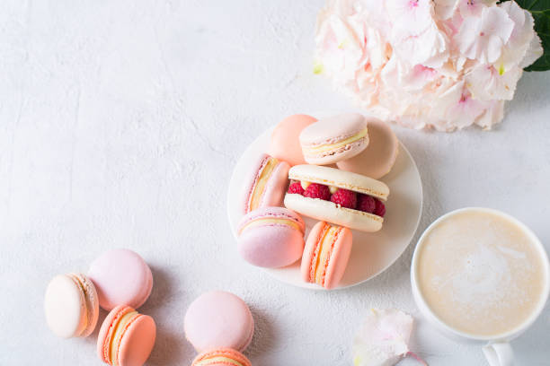 istock Macaroons and cup of coffee with flowers over white texture 956017088
