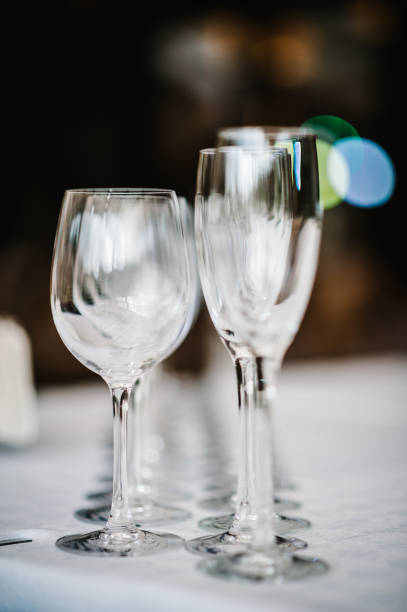 istock Empty glass for wine and champagne stand on white table. Close up. Empty glasses for elite drinks stand in two rows. 956019564