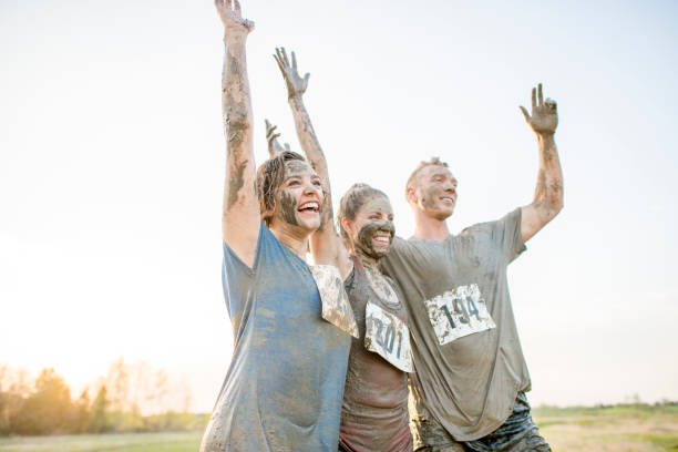 heureux jeunes adultes - mud run photos et images de collection