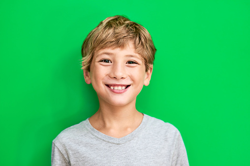 Studio portrait of a young boy standing against a green background