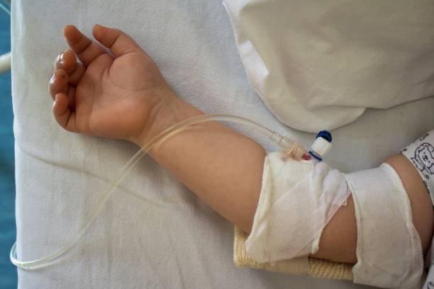 kind im krankenhausbett mit kochsalzlösung intravenös. wenig geduld - kochsalzlösung infusion stock-fotos und bilder