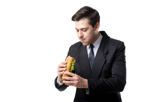 istock Young businessman in tie and suit eats hot dog 956032680