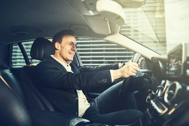 istock Young businessman smiling while driving through the city 956036196
