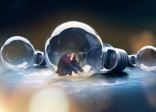istock Sad man is sitting in a large lamp, scale effect 956039110