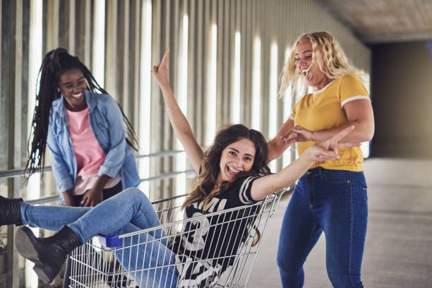 istock Girlfriends having fun with a shopping cart at night 956039514