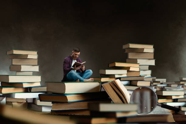 The single lifestyle and modern manhood. Relaxing middle aged bachelor at home choosing a book and reading lit by the morning sunlight.