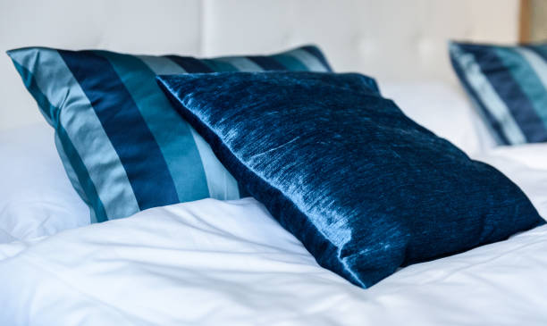 istock Blue silky hotel room bedding pillows and sheets on bed. 956041570
