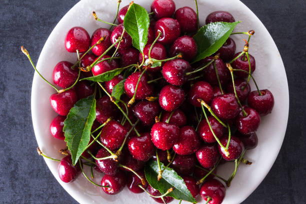 istock Fresh red ripe cherries on white plate 956045526