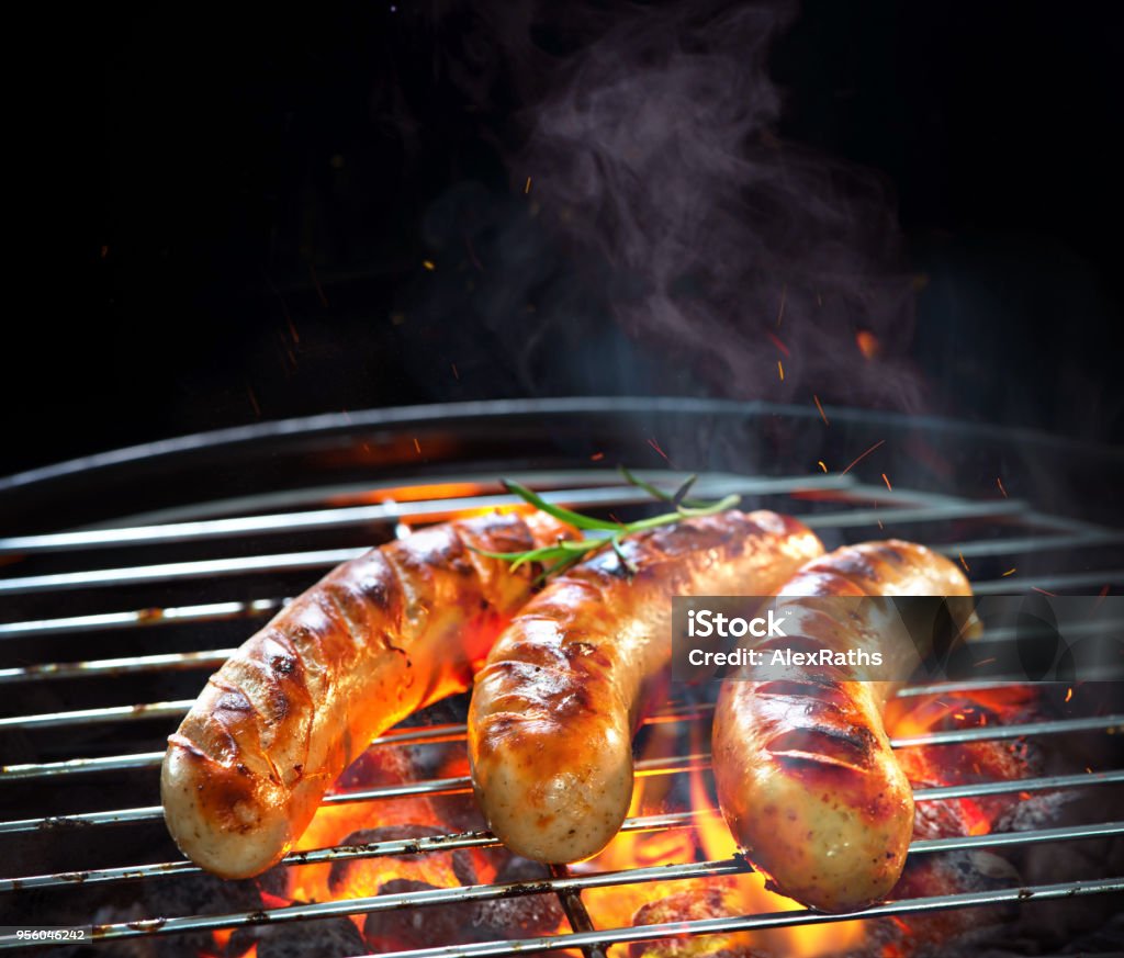 Saucisses grillées sur le barbecue avec la fumée et des flammes - Photo de Saucisse libre de droits