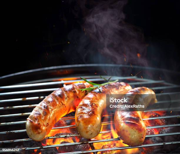 Photo libre de droit de Saucisses Grillées Sur Le Barbecue Avec La Fumée Et Des Flammes banque d'images et plus d'images libres de droit de Saucisse