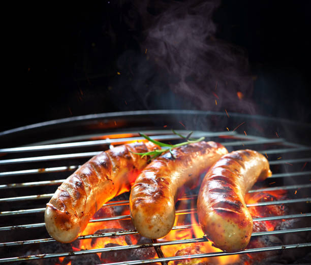 grilled sausages on grill with smoke and flame - sausage bratwurst barbecue grill barbecue imagens e fotografias de stock