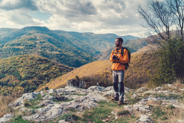 istock Tourist man with camera exploring the mountain and taking photos 956046966