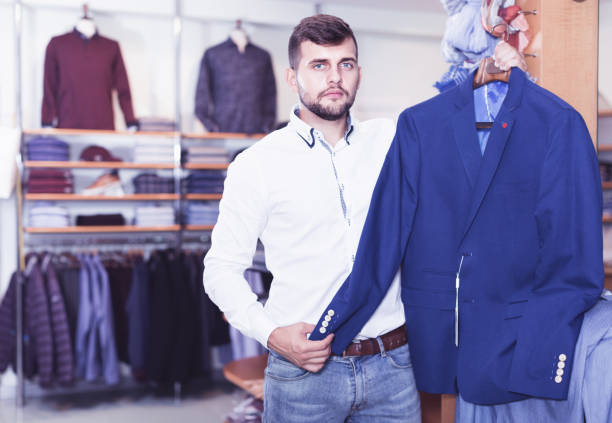 istock Handsome adult guy  choosing modern jacket in men store 956060860