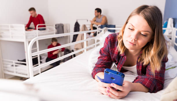istock Girl with phone lying on bed in hostel 956062206