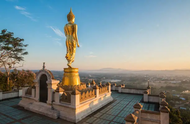 Photo of The iconic standing Buddha on Wat Phra That Khao Noi one of the most tourist attraction places in Nan province of northern Thailand during the sunrise.