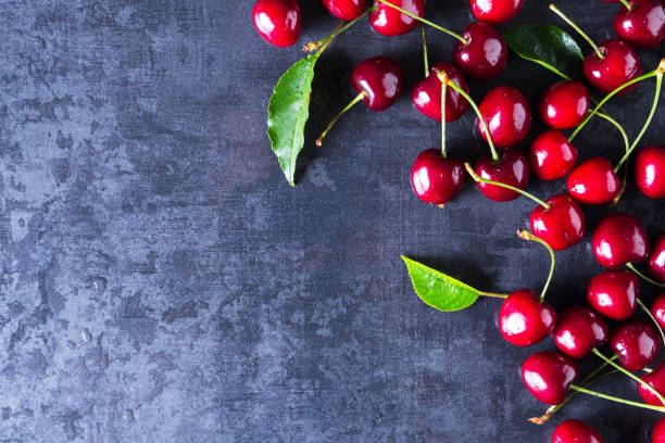 istock Fresh red ripe cherries on dark grey table 956066070