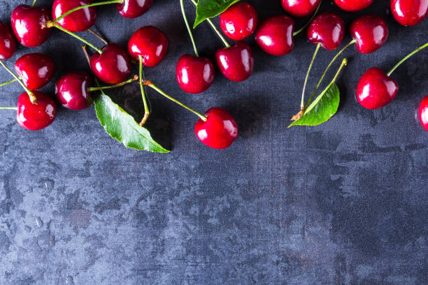 istock Fresh red ripe cherries on dark grey table 956066334