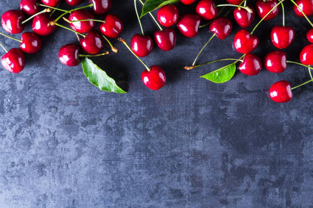 istock Fresh red ripe cherries on dark grey table 956066602