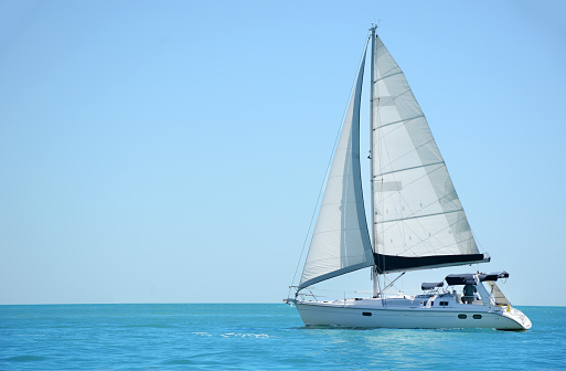 A dreamlike aerial drone shot of a beautiful sailing boat on lake with sparkling waters. The riverscape looks great and gorgeous