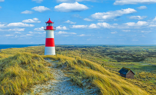 Red and white lighthouse with moody sky at Ellenbogen on island Sylt, Germany