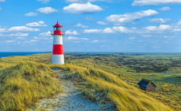 Red and white lighthouse with moody sky at Ellenbogen on island Sylt, Germany Red and white lighthouse with moody sky at Ellenbogen on island Sylt, Germany north sea photos stock pictures, royalty-free photos & images