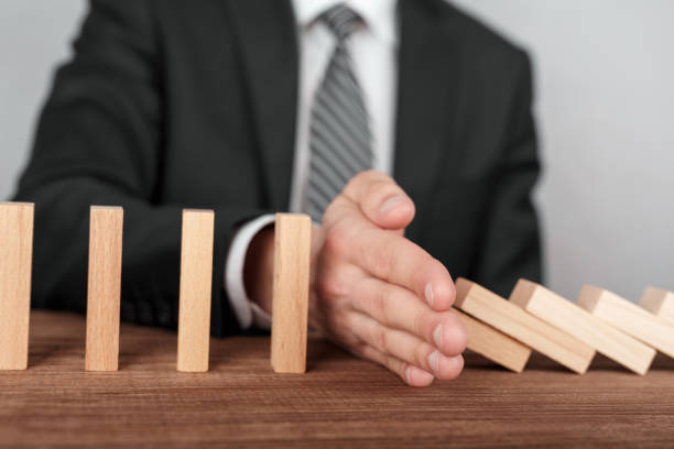 istock Businessman stopping domino effect with his hand. Security and insurance concept 956067564