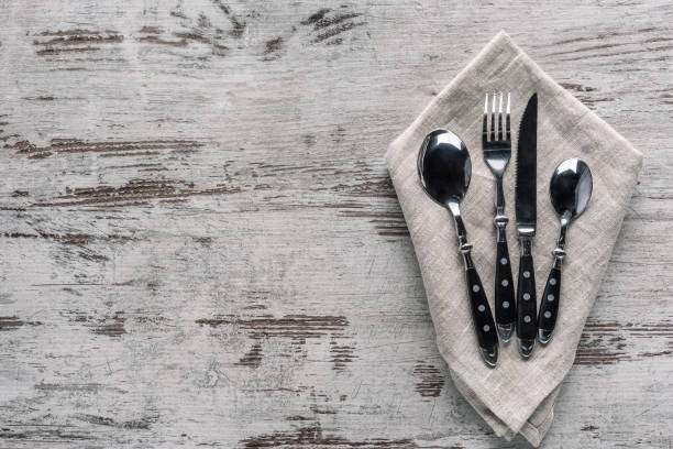 istock Set of dinner silverware with napkin on wooden table 956071668