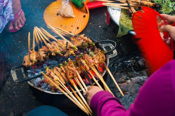 Hawker prepare the skewered grilled meats at street of Hoi An, a popular local street food of Vietnam