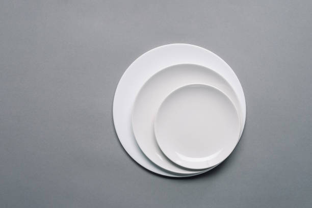 istock White plates of different sizes on grey background 956076396