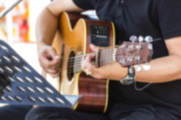 istock Blurred Image - Man Playing acoustic guitar in the room 956076910