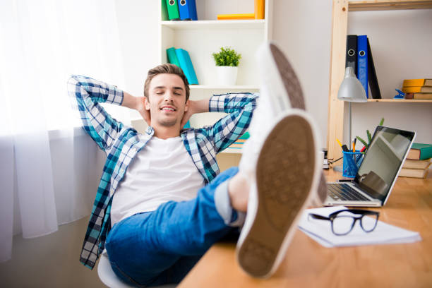 istock happy man holding legs on table and resting 956086382