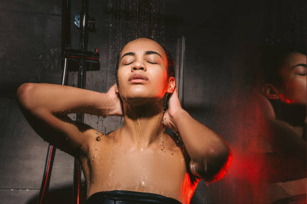 attractive african american woman washing hair in shower attractive african american woman washing hair in shower black woman washing hair stock pictures, royalty-free photos & images