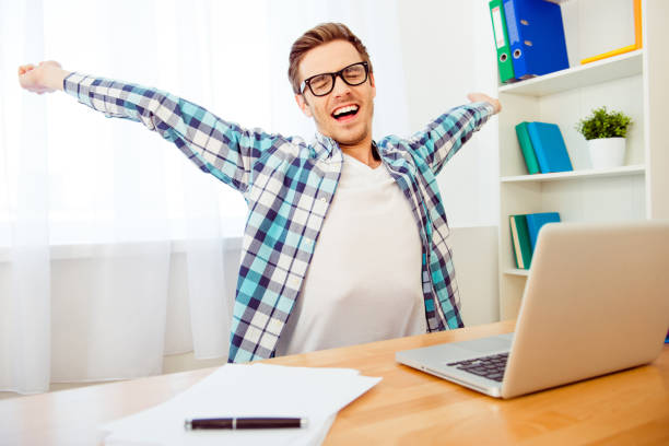 istock Handsome man in glasses stretching and yawning after long workin 956096168