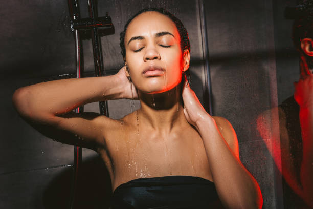 attractive african american woman with closed eyes washing hair in shower attractive african american woman with closed eyes washing hair in shower black woman washing hair stock pictures, royalty-free photos & images